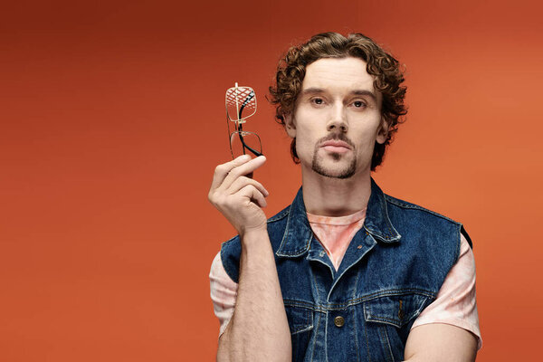 Человек с вьющимися волосами выражает эмоции на ярком фоне.