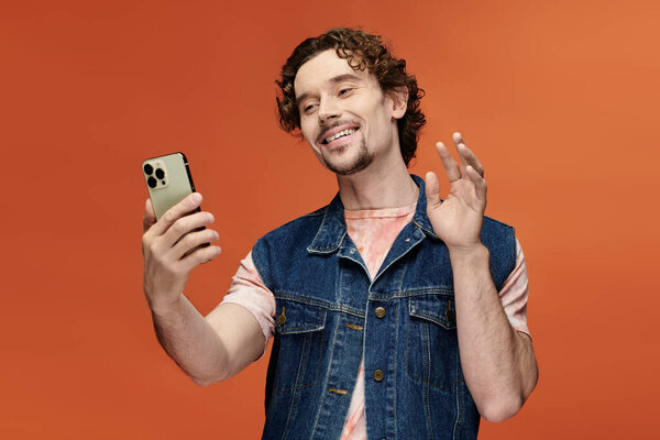 Человек улыбается и соединяется с друзьями на своем смартфоне на ярком фоне.