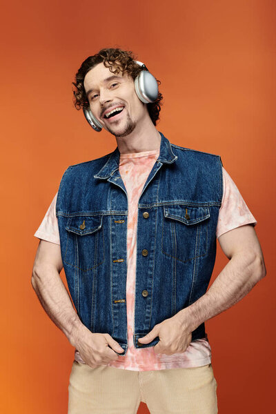 Радостный человек в наушниках позирует с уверенностью на ярком фоне.