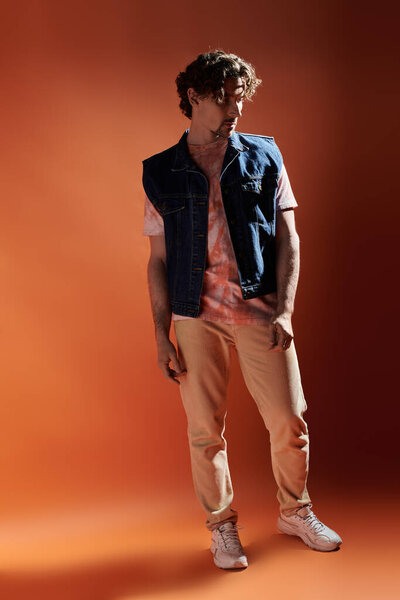 Стильный мужчина запечатлевает эмоциональный момент перед смелым фоном.