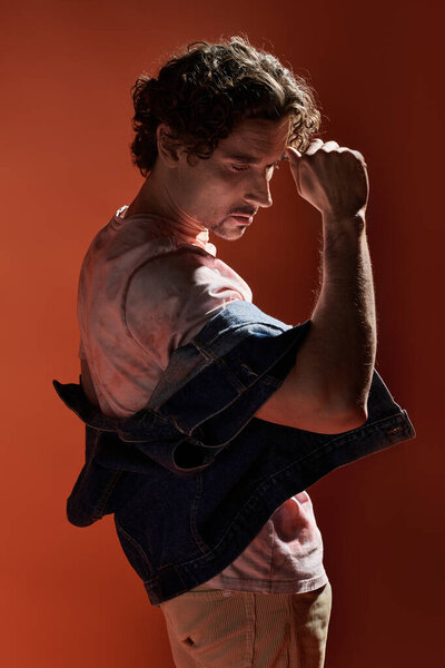 Человек выражает глубокие эмоции, позируя на ярком фоне..