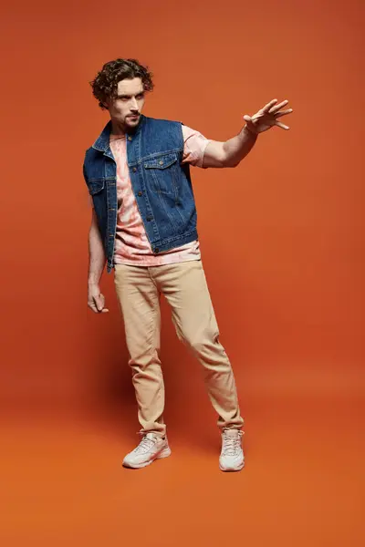 stock image A handsome man expresses emotion while posing on a vivid orange background.