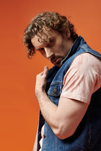 Красивый мужчина выражает эмоции, позируя на ярком фоне.