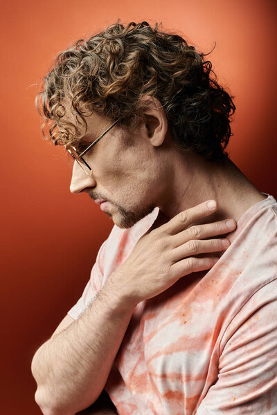 Красивый мужчина выражает эмоции, задумчиво позируя на ярком фоне..