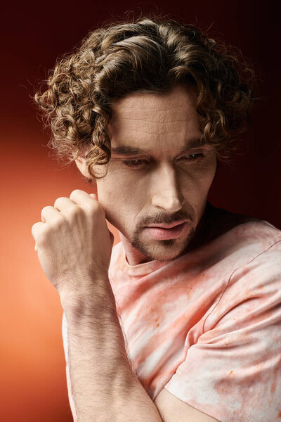 Красивый мужчина передает глубокие эмоции на фоне яркого фона.