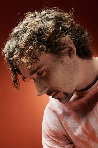 Красивый мужчина задумчиво позирует на ярком фоне, передавая глубокие эмоции.