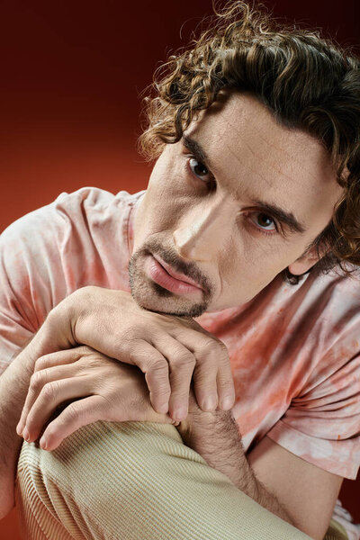 Задумчивый человек выражает глубокие эмоции на ярком фоне.