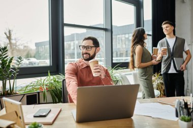 Good-looking colleagues sip coffee while in modern office.