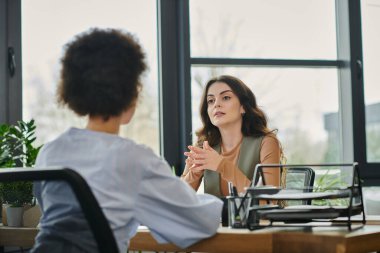 Two colleagues converse about layoffs in a stylish office environment. clipart