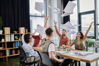 Meslektaşlar birlikte zaman geçirirken keyifle kağıtları fırlatırlar..