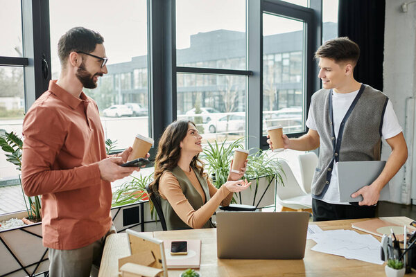 Три коллеги общаются за чашкой кофе в современном офисе.