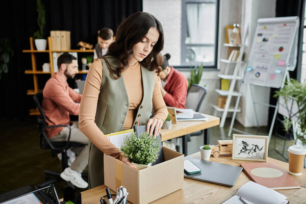 Professional delicately pack items amidst an emotional transition, colleagues on backdrop.