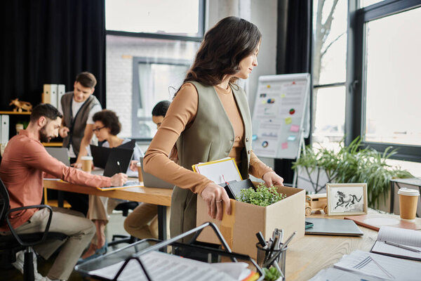 Женщина выражает эмоции при подготовке к переходу, коллеги на заднем плане.