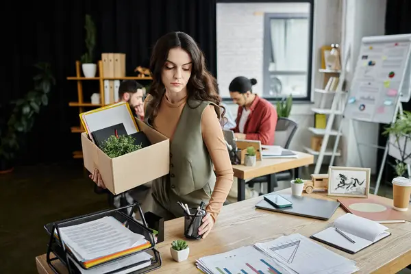 stock image Woman in stylish attire pack up belongings amid an office layoff, colleagues on backdrop.