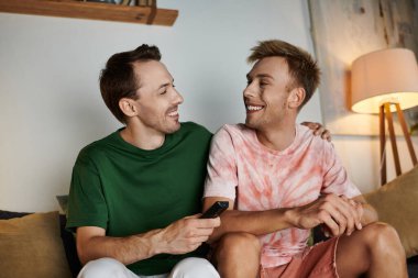 Sıcak ve davetkar bir ortamda iki erkek gülüşür ve güler..