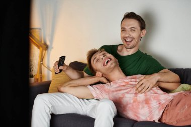 İki adam evlerindeki kanepede gülüşür ve sevişir..