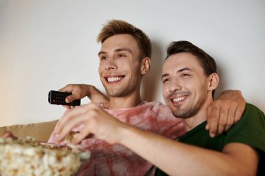 İki adam kanepede sarılıp, film izlerken kahkahalar atıyorlar..