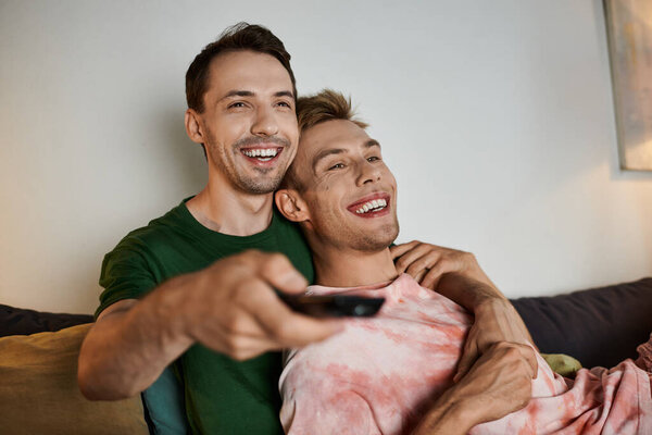 A couple relaxes on the couch, sharing laughter and love while watching TV.