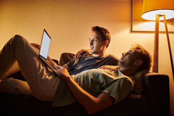 Двое мужчин отдыхают вместе на диване, деля тихие моменты дома.