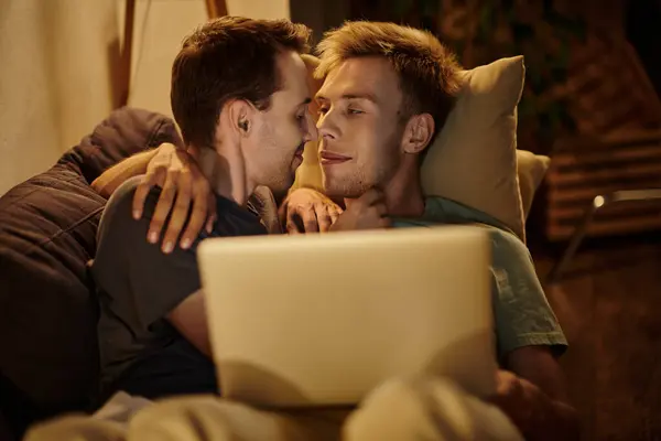 stock image Two men share a tender moment while relaxing on the couch with a laptop.