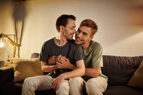 Двое мужчин нежно обнимаются, наслаждаясь уютным вечером дома.