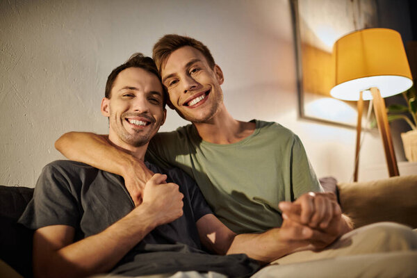 Двое мужчин разделяют теплые объятия, наслаждаясь друг другом дома.