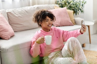 Genç bir kadın kanepede dinleniyor, telefonda konuşurken gülümsüyor..