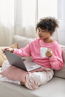 Laptopuyla çalışırken kahvesini yudumluyor, evde rahat bir günün tadını çıkarıyor..