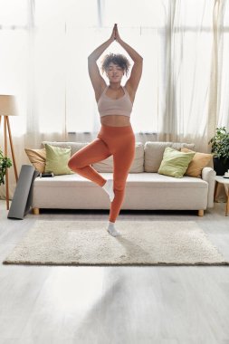 Zarif bir kadın yoga pozunda dengede durur, sıcaklıkla ve rahatlıkla çevrili..