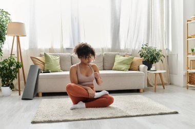 A young woman engages in mindfulness practice in her inviting home space. clipart