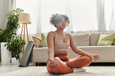 Genç bir kadın rahat evinde sessizce meditasyon yapıyor..
