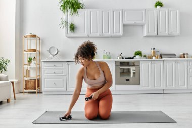 Güzel bir kadın, güneşli bir mutfakta yoga rutininden zevk alır..