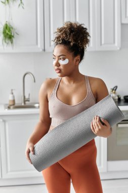 A young woman prepares for yoga while practicing self care at home. clipart