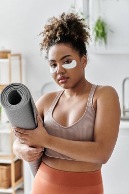 Embracing self care, a woman holds her yoga mat with a calming mask on. clipart