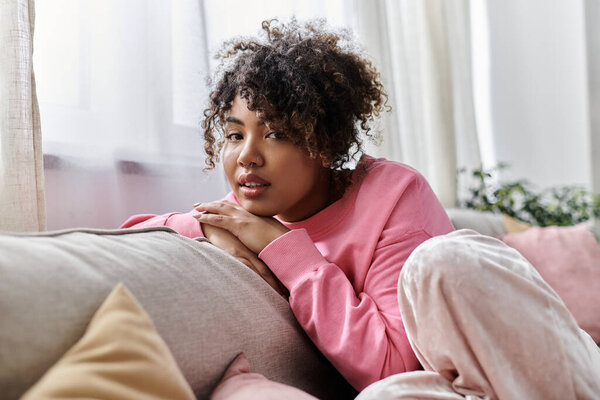 Молодая женщина расслабляется дома, наслаждаясь мирным моментом на диване.