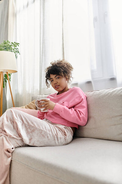 Молодая женщина наслаждается теплым напитком, сидя на диване.