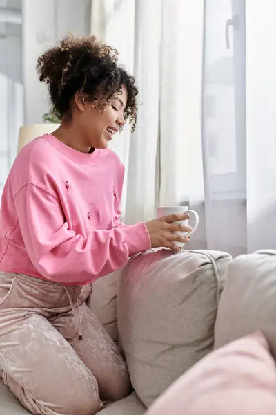 stock image A young woman savors a warm drink in a comfortable living space.