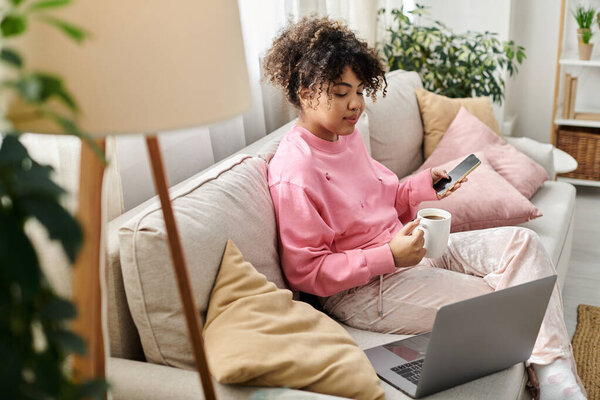 A young woman relaxes at home with coffee while using her phone.