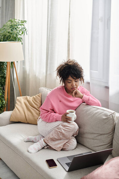 Отдых с теплой чашкой чая на удобном диване дома.