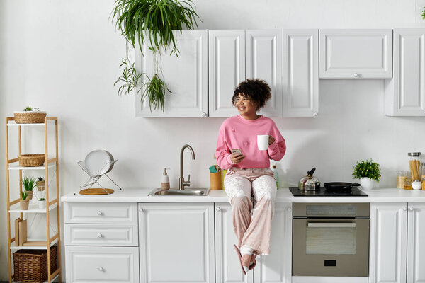A woman relaxes at home, sipping tea and embracing tranquility in her kitchen.