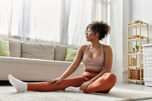 A young woman stretches elegantly on the carpet, enjoying her serene space.