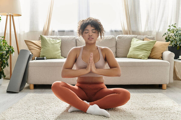 Молодая женщина практикует медитацию в уютном жилом пространстве.