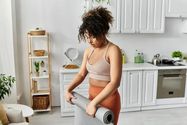 stock image Woman rolls up her yoga mat after a peaceful session in her stylish living space.