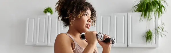 stock image A young woman engages in a workout routine at home, focused on her fitness.