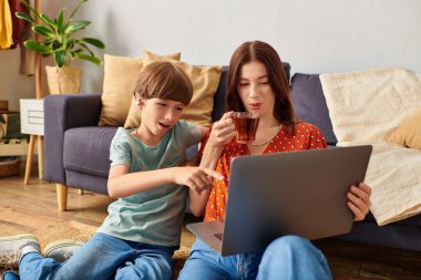 A hearing impaired child and his mother share a joyful moment with a laptop. clipart