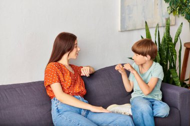 Bir anne ve işitme engelli oğlu kanepede sıcak bir sohbet ediyorlar..