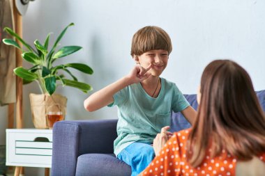 Bir anne, işitme engelli oğluyla şakalaşır, gülümser ve bağ kurar..