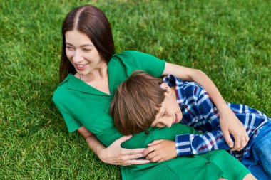 A mother and her hearing impaired son share a joyful moment in a lush green park. clipart