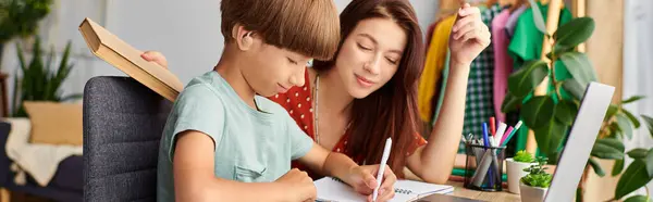 stock image A caring mother guides her son as he happily learns and draws.