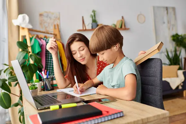 stock image A mother engages her son in creative learning at their shared workspace.